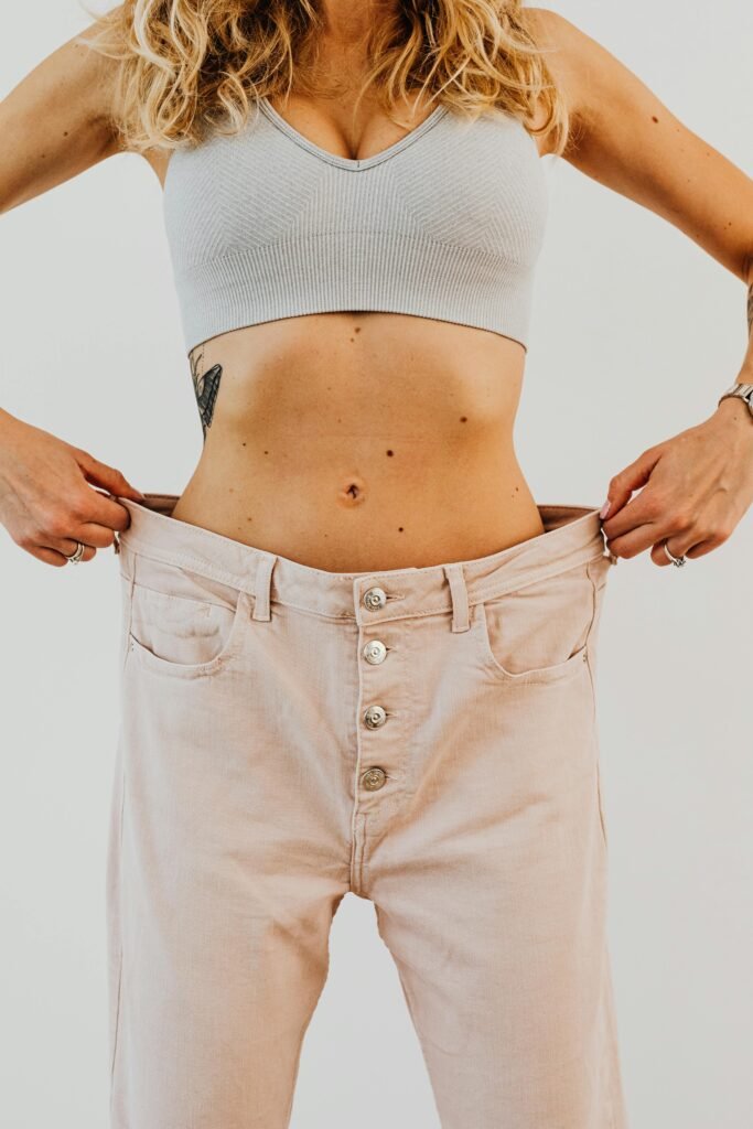 woman showing weight loss results wearing oversized pants Georgetown TX